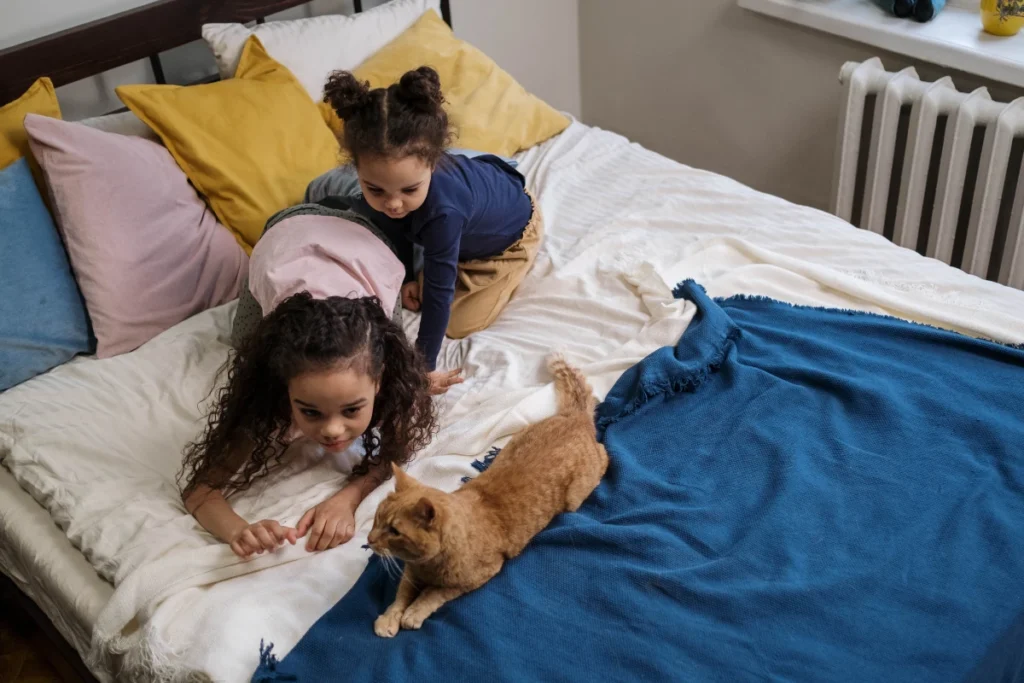 Mačka robí na posteli spoločnosť malým deťom